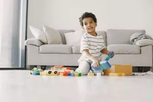 ילד קטן משחק עם צעצועים בחדר הסלון.