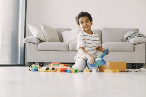 ילד קטן משחק עם צעצועים בחדר הסלון.